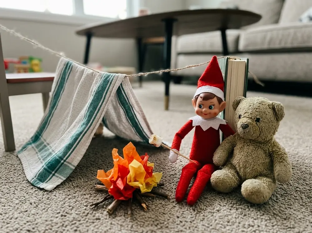 Toy elf doll pitches a tea-towel tent over string, with a paper campfire, marshmallow on a toothpick, and a stuffed-animal camp buddy