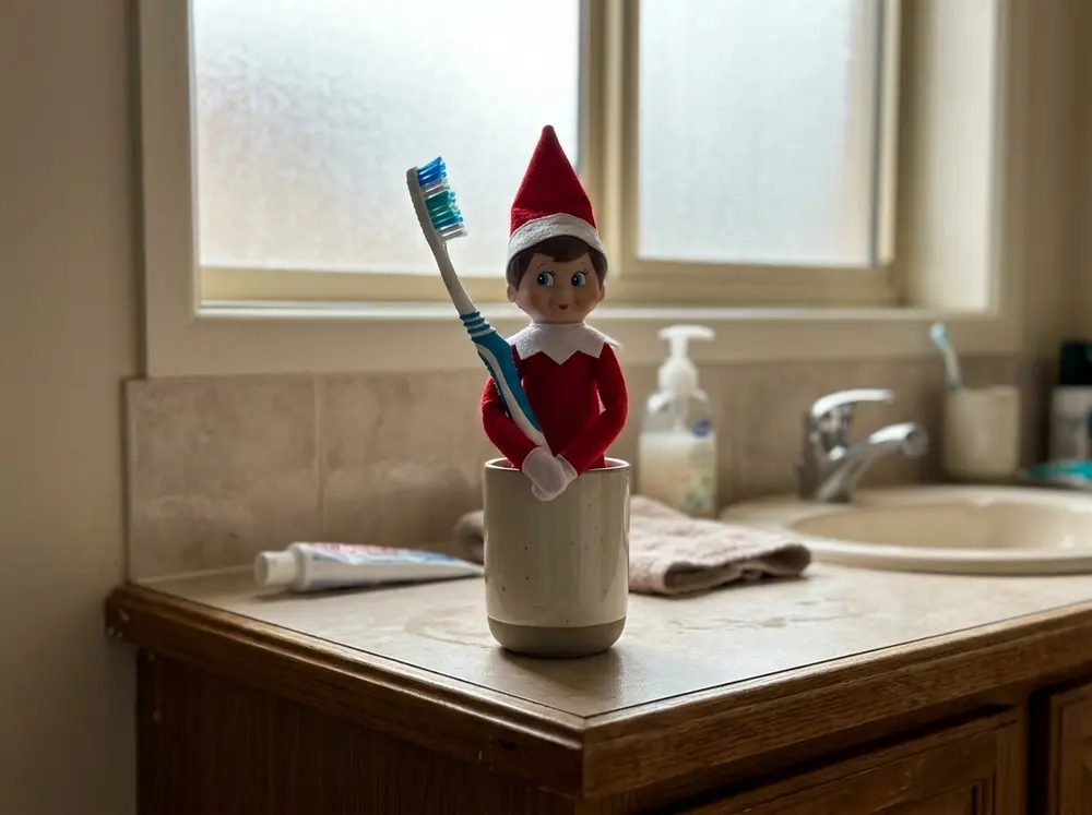 Stand the toy elf doll in the bathroom cup holding a toothbrush twice its size
