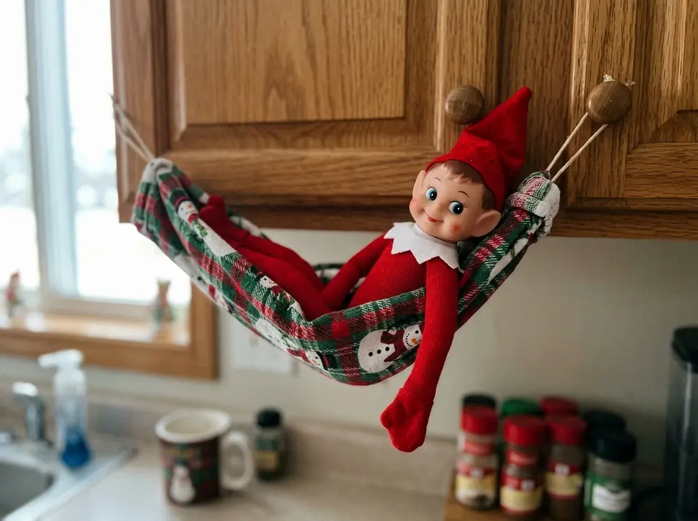 String a dish towel between two chair backs or cabinet knobs as a hammock; the toy elf doll naps in it, one arm dangling