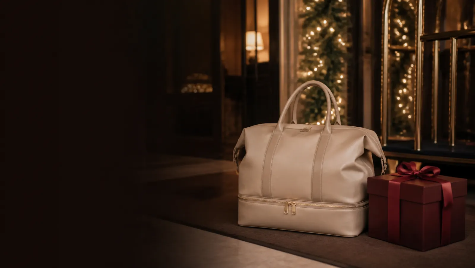 Representative beige weekender bag beside a burgundy Christmas gift box