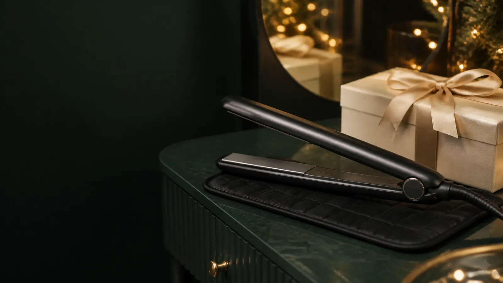 Representative black hair straightener beside a cream Christmas gift box