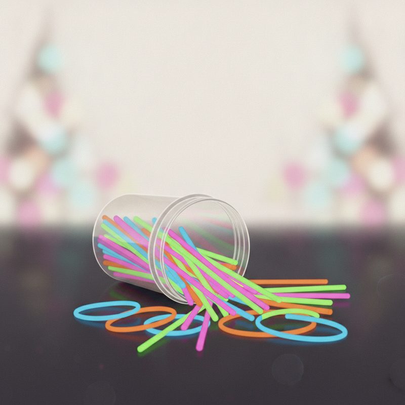 Representative tub of colourful glow sticks spilling onto a dark table